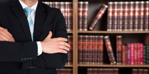 man with arms crossed and book shelves