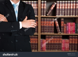 man with arms crossed in front of book shelves