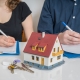 man and woman with pen and paper, model house and keys in front of them representing division of property