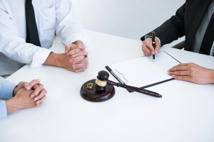 a couple and a lawyer sitting at a white table working on a divorce agreement